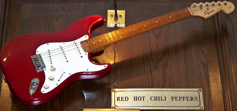 Red Hot Chili Peppers Squier Stratocaster Guitar in a display case.